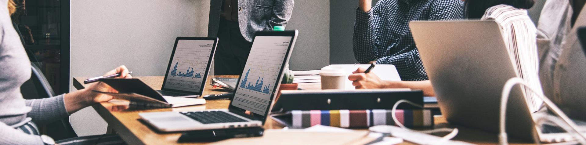 Man standing pointing at whiteboard, presenting to room of professionals