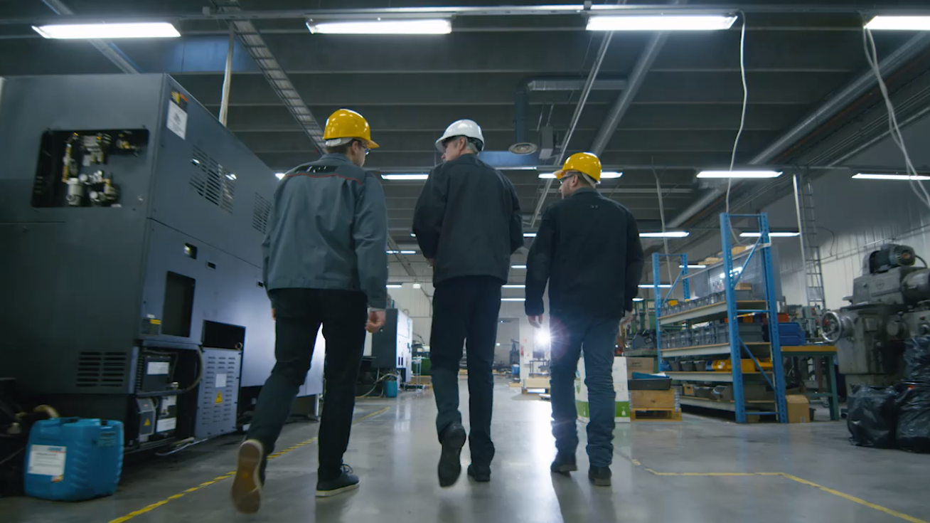 3 men tour a warehouse wearing hardhats