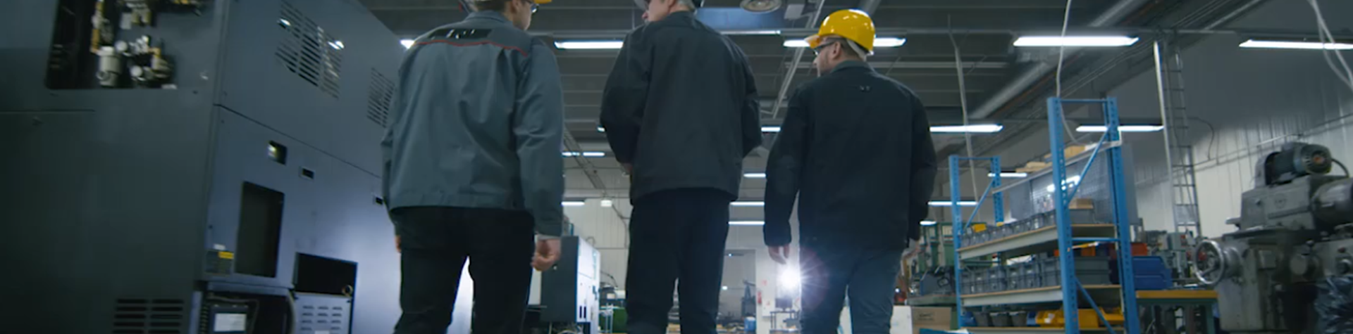 3 men tour a warehouse wearing hardhats