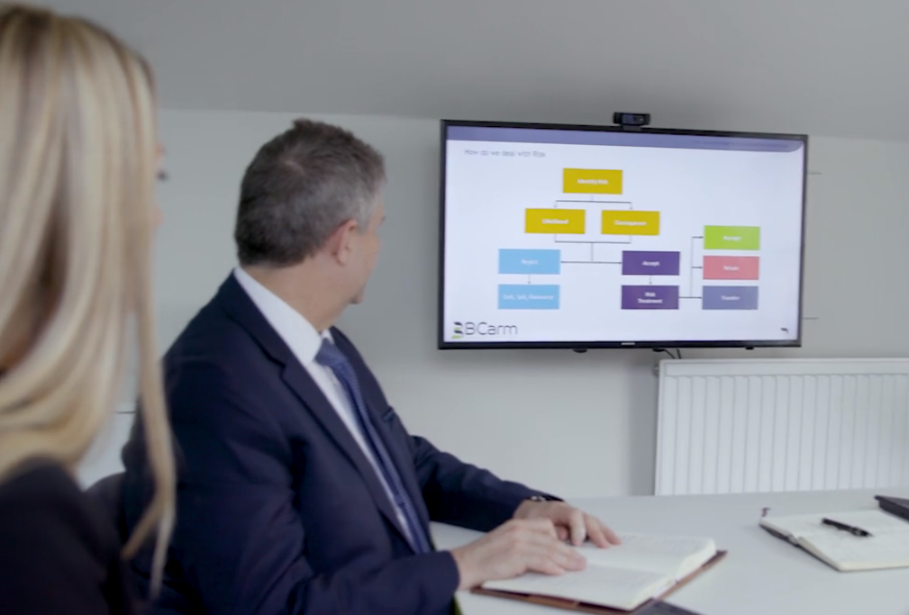 Boardroom of people talk to a man video conferencing them on a large TV screen