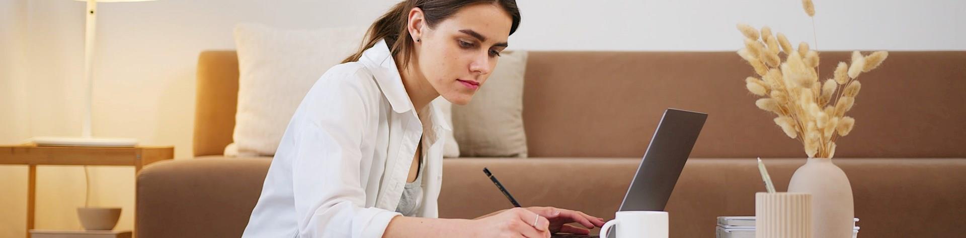Woman e-learning using a laptop on a coffee table