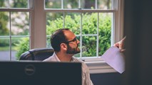 document being handed over to someone sitting in front of a computer