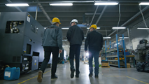 3 men tour a warehouse wearing hardhats